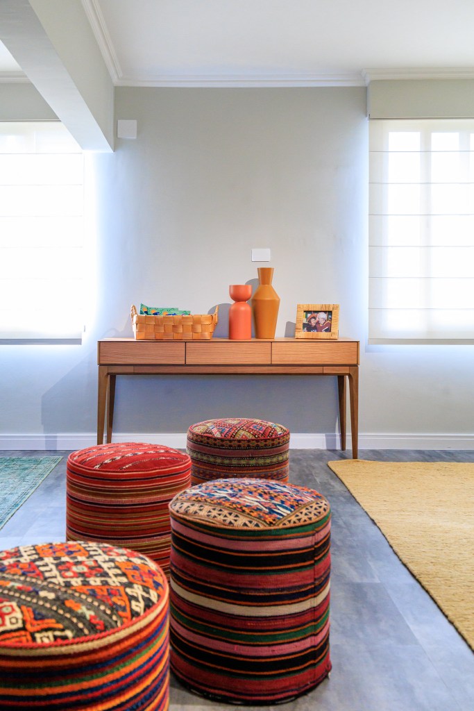 Sala é inspirada na obra de Zé Celso e na exuberância da Amazônia. Projeto de Jordana Fraga. Na foto, sala, pufes coloridos, aparador, vaso.