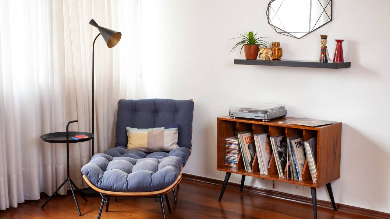 Sem quebra-quebra, apê ganha nova atmosfera com móveis e texturas. Projeto de Abrazo Interiores. Na foto, sala de estar, cantinho de leitura, poltrona costela azul, luminária de piso, rack com discos de vinil.