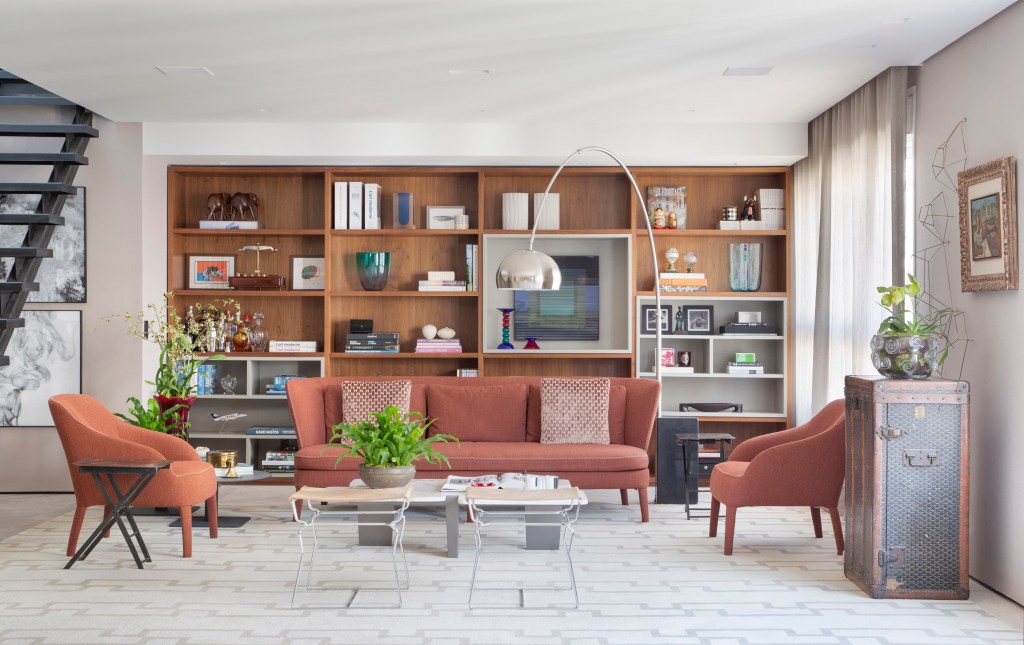 Tapete integra espaços da área social desta cobertura de 500 m². Projeto de DB Arquitetos. Na foto, sala de estar, poltrona e sofá terracota, estante de marcenaria.