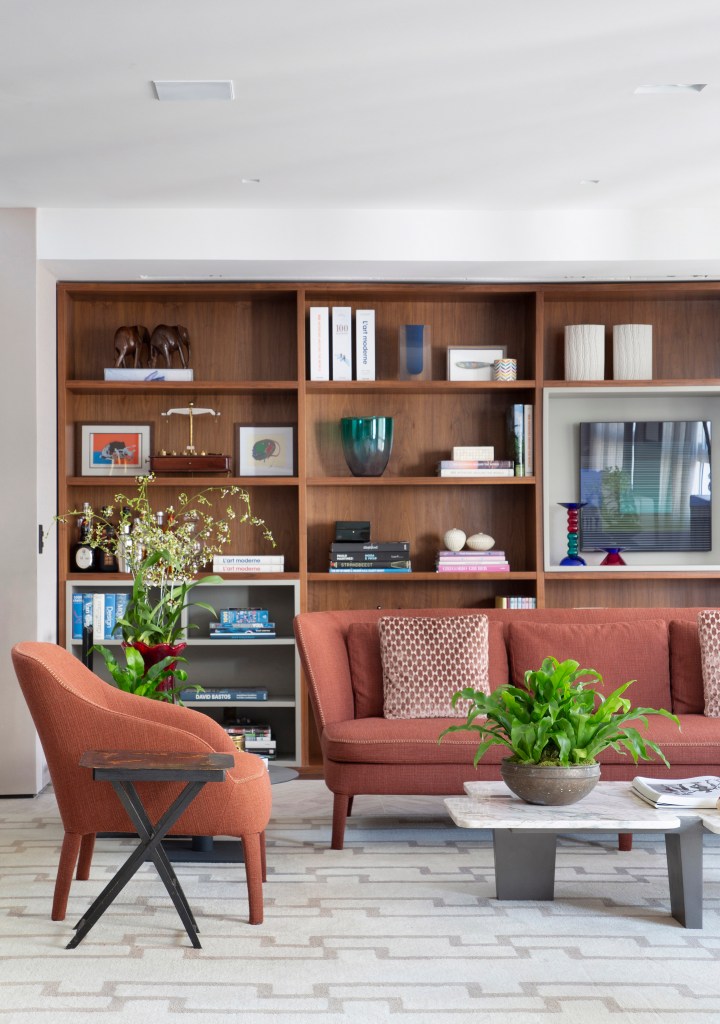 Tapete integra espaços da área social desta cobertura de 500 m². Projeto de DB Arquitetos. Na foto, sala de estar, poltrona e sofá terracota, estante de marcenaria.