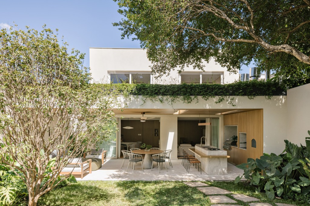Vão de 9 m integra esta casa de 350 m² ao jardim. Projeto de Alexandre Dal Fabbro. Na foto, varanda com churrasqueira e telhado verde.