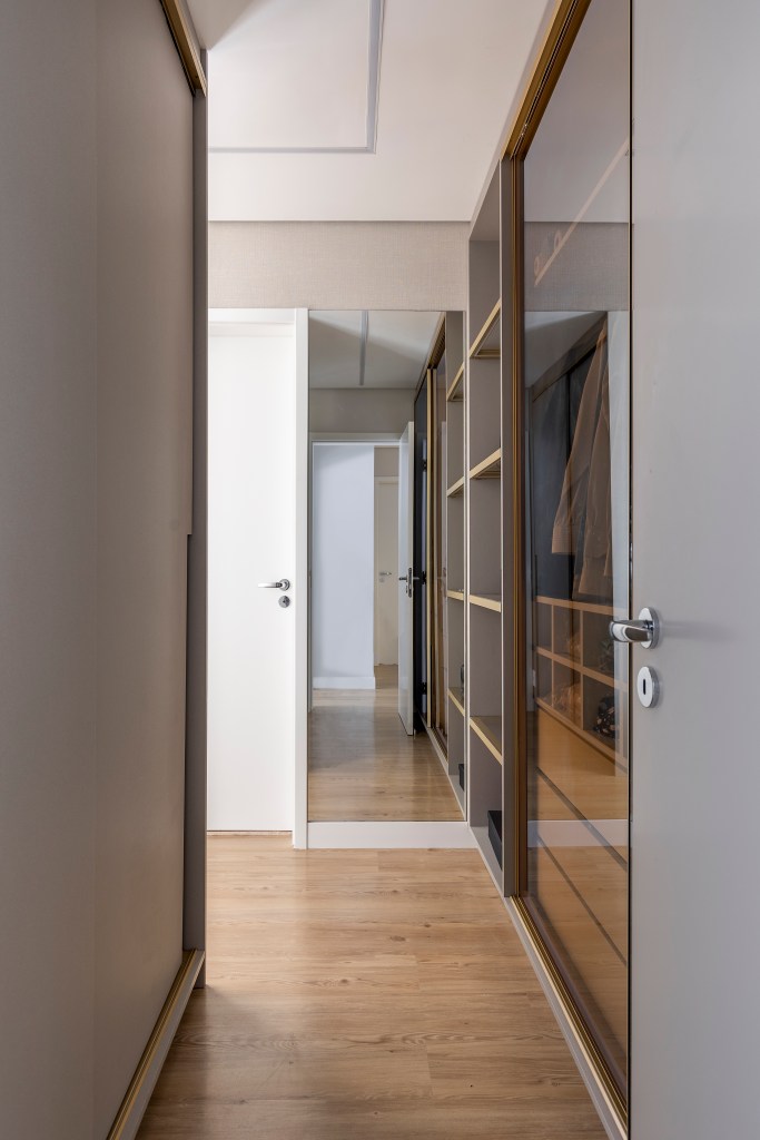 Varanda de apê tem dois espaços: um gourmet e outro de estar. Projeto de Blaia e Moura. Na foto, closet com armários com portas espelhadas.