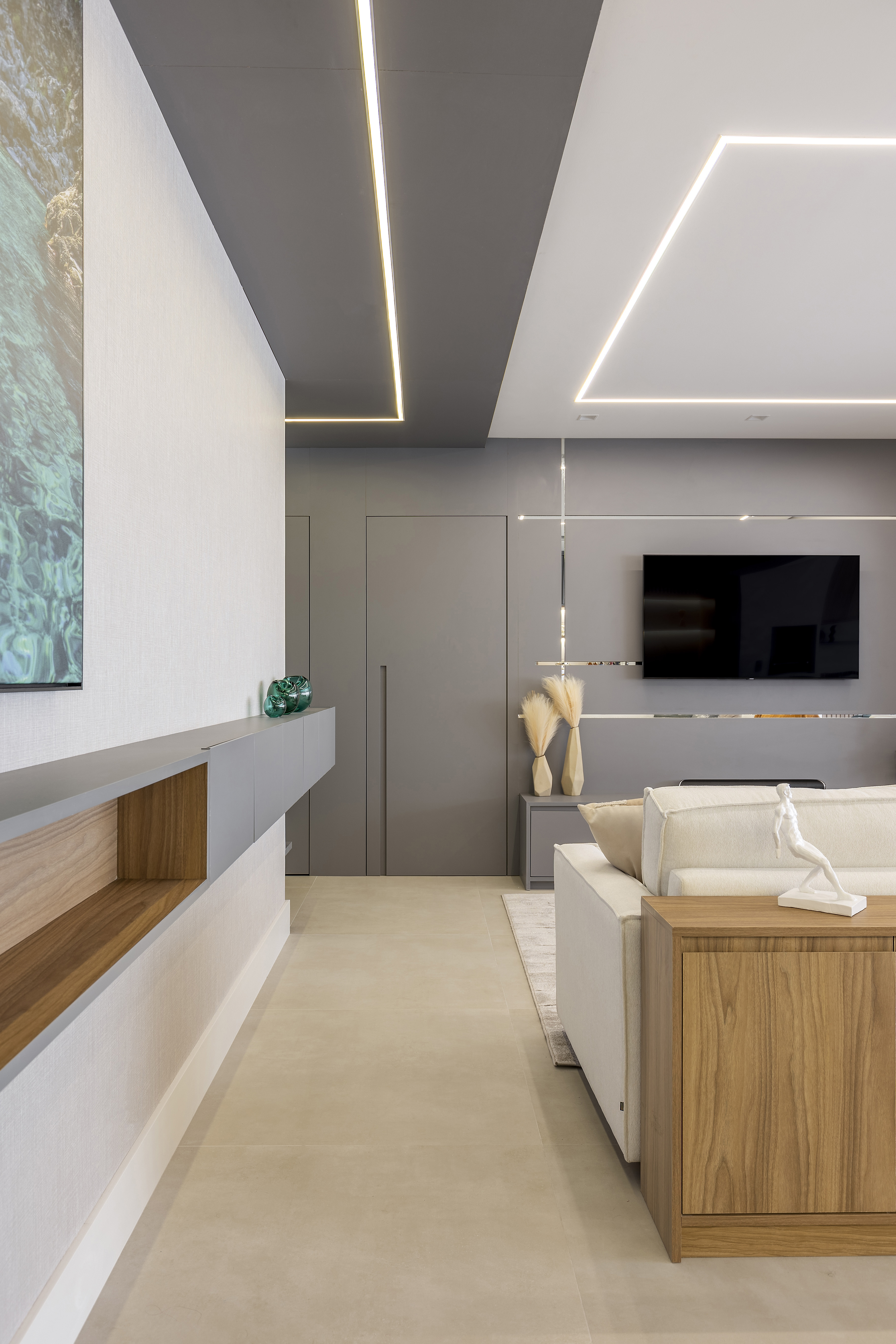 Varanda de apê tem dois espaços: um gourmet e outro de estar. Projeto de Blaia e Moura. Na foto, sala de estar, aparador aéreo, teto com iluminação com fitas de LED.