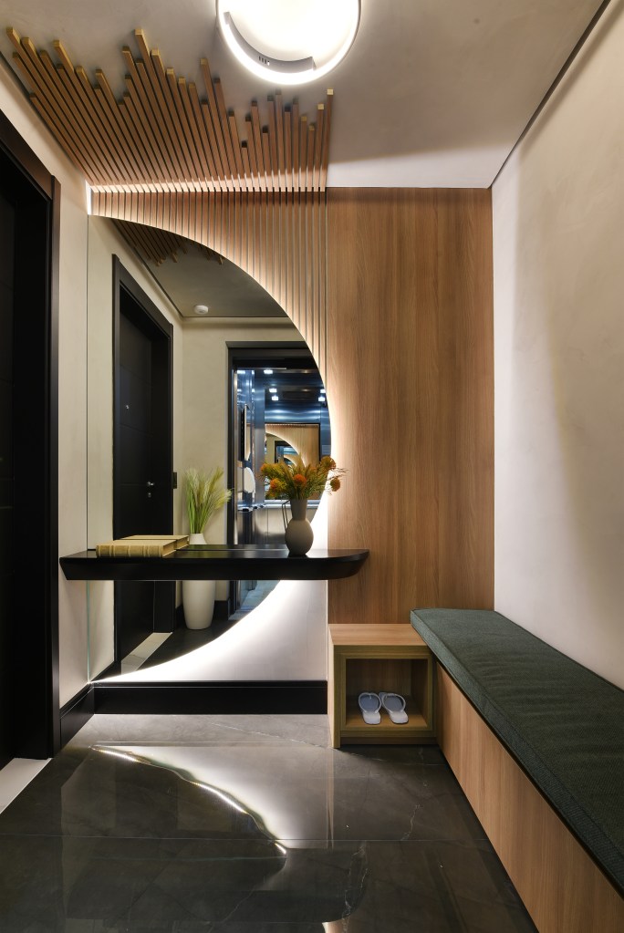 Varanda de estar gourmet é destaque em apartamento de 204 m². Projeto de Rosangela Pena. Na foto, hall de entrada com espelho em forma de semicírculo iluminado, aparador, banco.