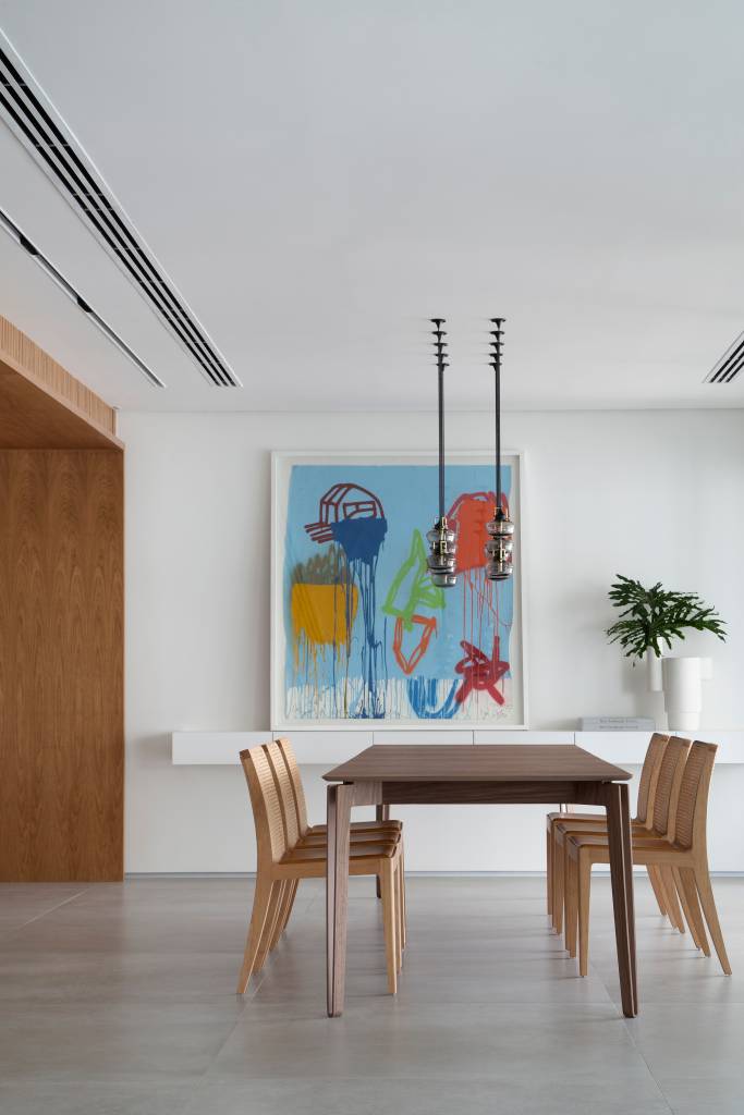 Venezianas em madeira trazem privacidade aos espaços de apê minimalista. Projeto de PKB Arquitetura. Na foto, sala integrada, piso de porcelanato, mesa de jantar, quadro.