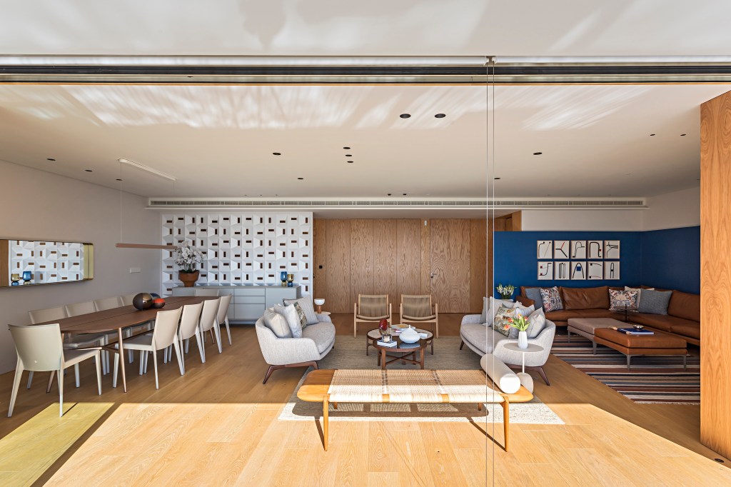 Apartamento Estoril, em Portugal, ganha décor com brasilidade. Projeto de Andrea Chicharo. Na foto, sala integrada, piso de madeira, sofá branco.