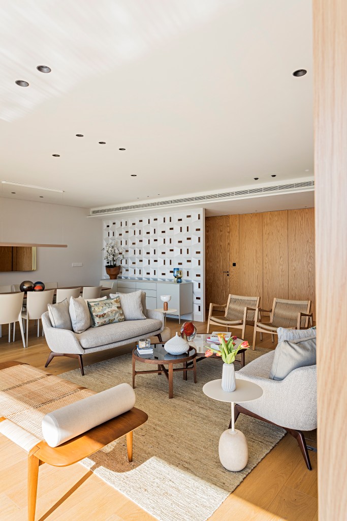 Apartamento Estoril, em Portugal, ganha décor com brasilidade. Projeto de Andrea Chicharo. Na foto, sala integrada, sofá neutro, cobogó branco, painel de madeira.