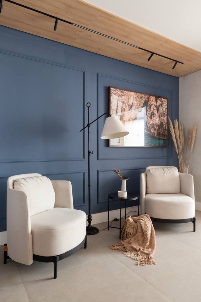 Apartamento une a personalidade da família de quatro moradores no décor. Projeto de Art2 Arquitetura. Na foto, living com parede azul e poltronas.