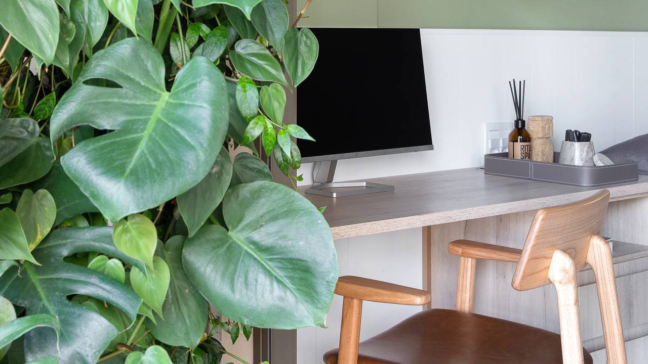 Apê clean de 93 m² tem cuba farm sink, espelho giratório, brises e lambris. Projeto de Manoela Fleck. Na foto, home office, parede verde, prateleira, jardim vertical.