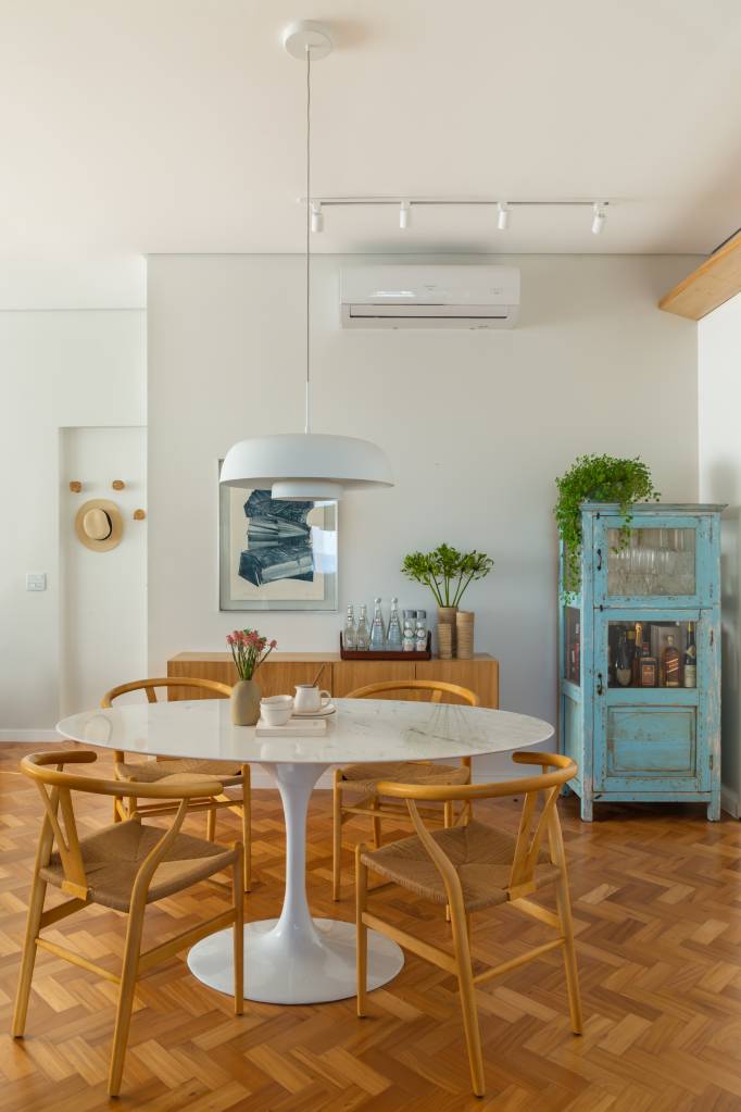 Apê ganha escritório com vista para o mar e texturas nas paredes brancas. Projeto Ateliê Concreto. Na foto, sala de jantar com mesa redonda, cadeiras e cristaleira.