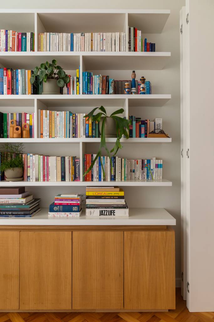 Apê ganha escritório com vista para o mar e texturas nas paredes brancas. Projeto Ateliê Concreto. Na foto, home office com prateleiras de livros.