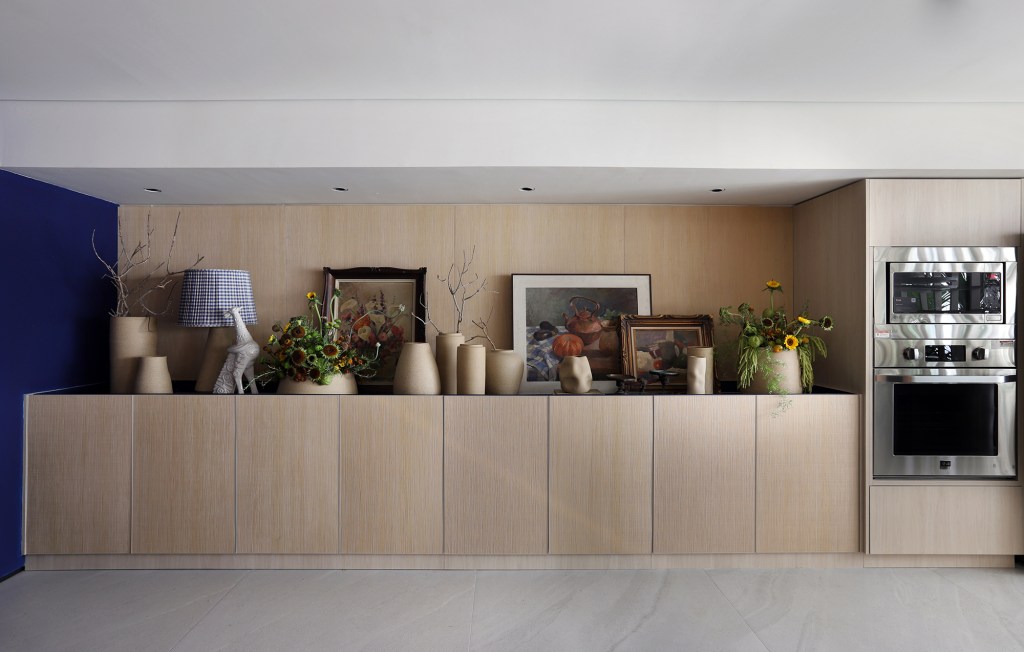 Cerâmicas artesanais compõem o tampo da mesa desta cozinha repleta de azul. Projeto de Mandril Arquitetura. Na foto, cozinha com armário e vasos de plantas.