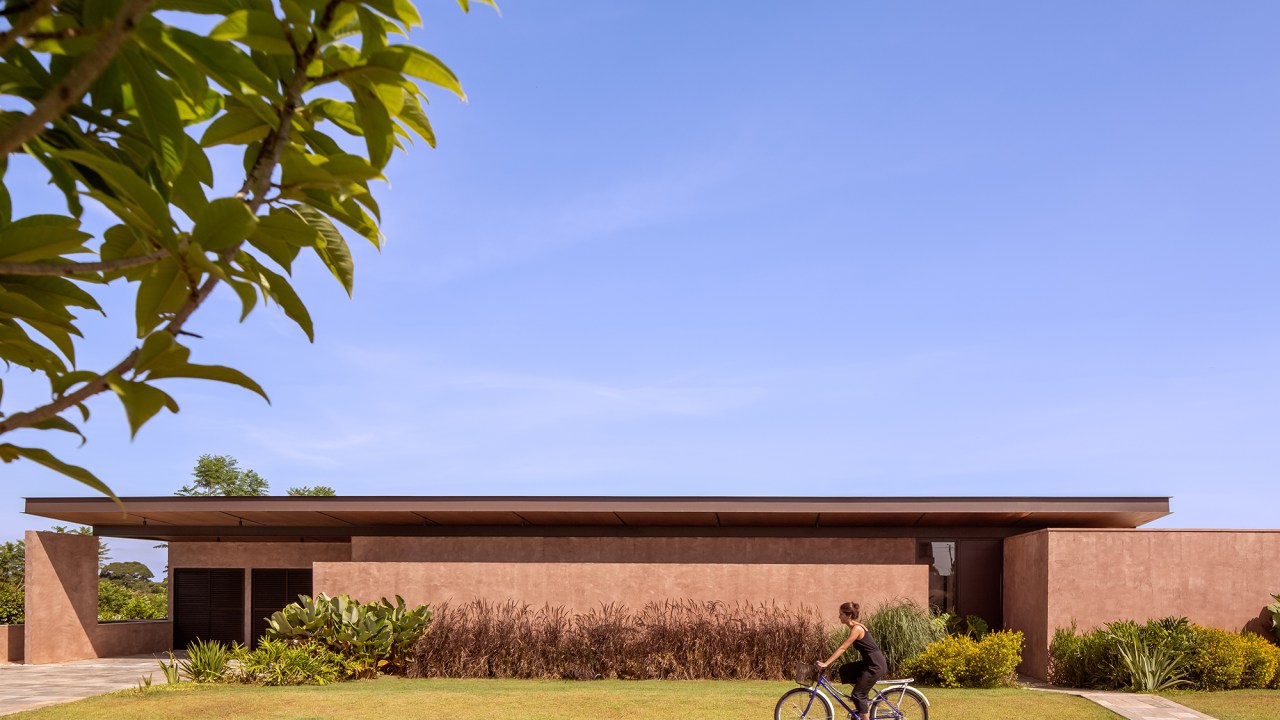 Cobertura metálica unifica os volumes desta casa de 568 m². Projeto de Vaga Arquitetura. Na foto, fachada com jardim.