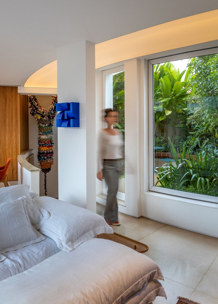 Cobertura com planta circular tem jardim interno, área gourmet e sauna. Projeto de Roberto Souto. Na foto, janela para jardim, sofá branco.