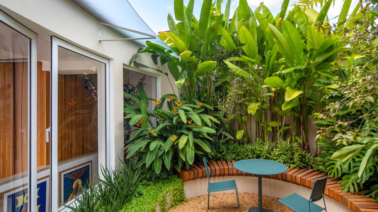 Cobertura com planta circular tem jardim interno, área gourmet e sauna. Projeto de Roberto Souto. Na foto, plantas, folhagens, mesa redonda pequena, cadeiras.