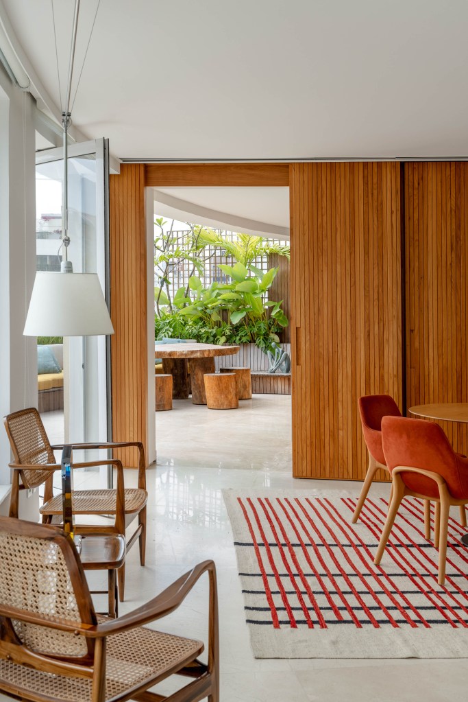 Cobertura com planta circular tem jardim interno, área gourmet e sauna. Projeto de Roberto Souto. Na foto, cadeiras com encosto de palhinha, luminária branca.