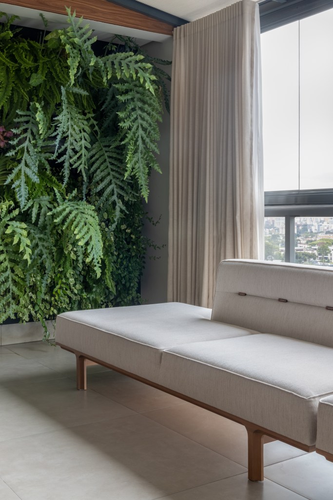 Cozinha integrada ao jardim é o coração deste apartamento de 282 m². Projeto Estudio Elmor. Na foto, varanda com sofá e parede verde.