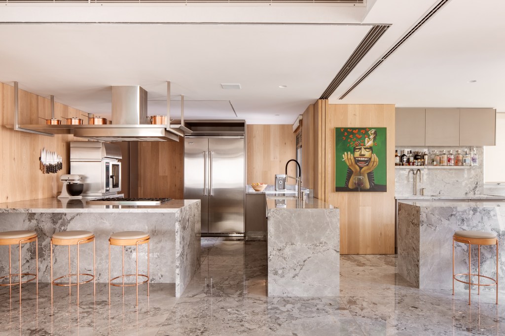 Cozinha revestida com quartzito é destaque no apê da chef Carol Magalhães. Projeto de DB Arquitetos. Na foto, ilha, bancada, banquetas, porta de correr.