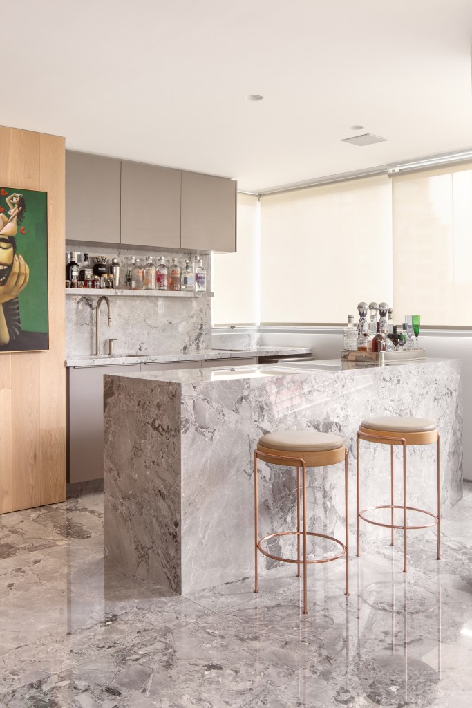 Cozinha revestida com quartzito é destaque no apê da chef Carol Magalhães. Projeto de DB Arquitetos. Na foto, ilha, bancada, banquetas, porta de correr.
