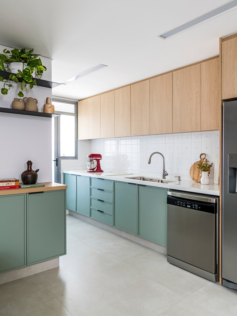 Dois escritórios e ampla área de receber caracterizam apê de 175 m². Projeto de Juliana Casadei. Na foto, cozinha com marcenaria verde, prateleiras e vasos.
