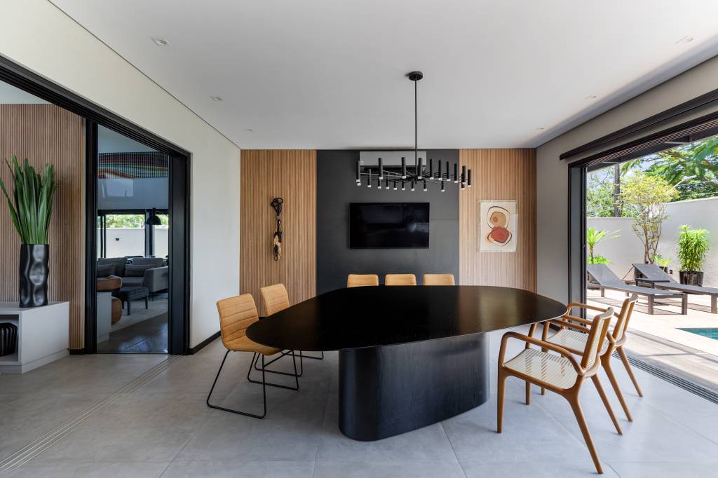 filetes-madeira-ecologica-revestem-entrada-casa-350-m-augusto-manzato-arquitetura-16 Filetes em madeira ecológica revestem entrada de casa de 350 m². Projeto de Augusto Manzato Arquitetura. Na foto, jantar, mesa em formato orgânico preta.