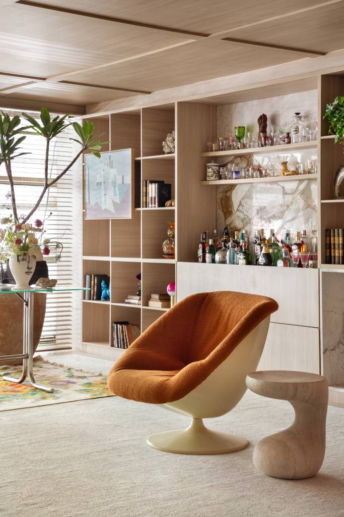 Home office de 45 m² tem estante de marcenaria e mármore e área de estar. Projeto de Rodolfo Consoli para a CASACOR São Paulo 2024. Na foto, poltrona e bar.