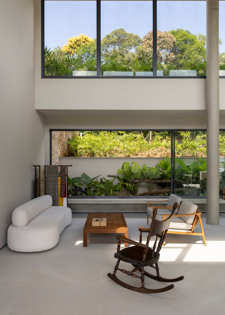 Inspirada no Japão, casa de 524 m² tira proveito da declividade do terreno. Projeto de Cité Arquitetura. Na foto, sala com poltronas e vista para o jardim.