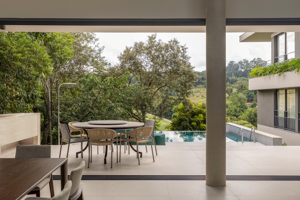 Inspirada no Japão, casa de 524 m² tira proveito da declividade do terreno. Projeto de Cité Arquitetura. Na foto, varanda com piscina, vista para o jardim e mesa.