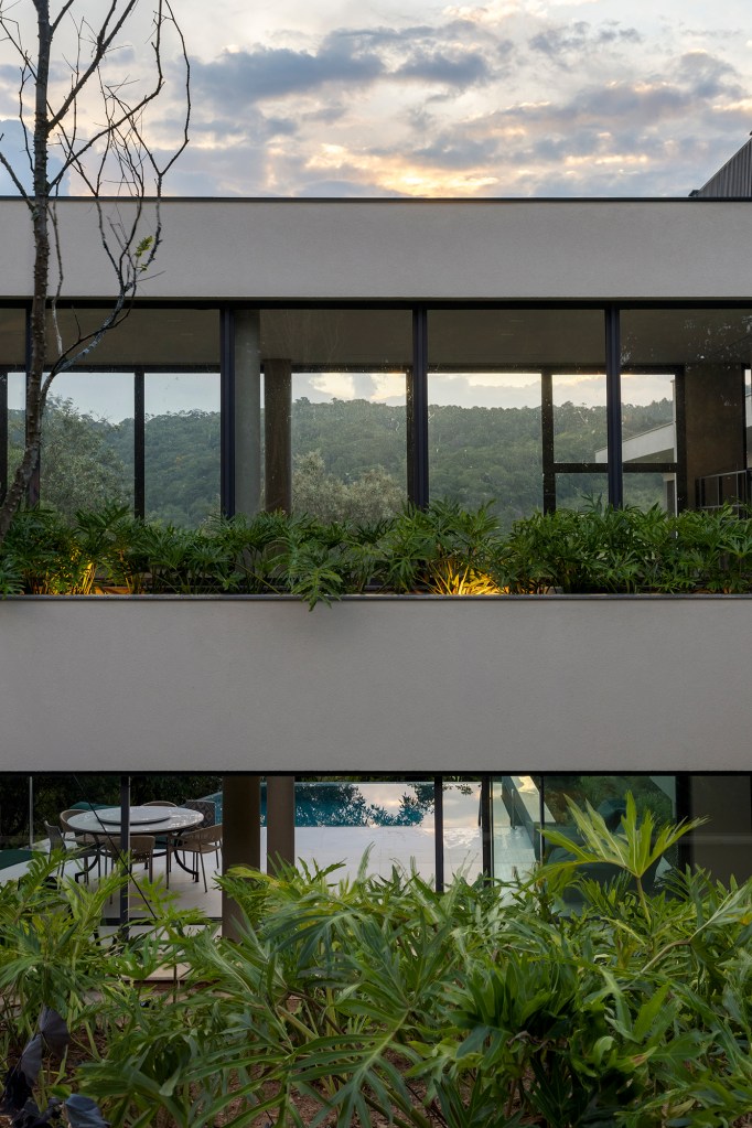 Inspirada no Japão, casa de 524 m² tira proveito da declividade do terreno. Projeto de Cité Arquitetura. Na foto, fachada da casa com janelas e jardim.