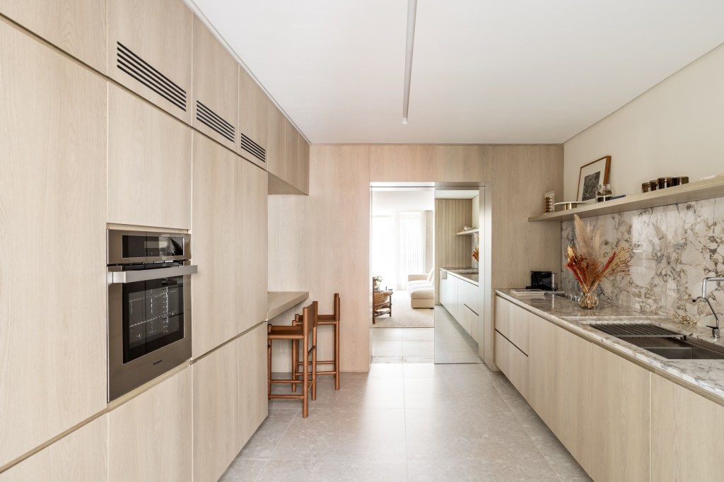 Marcenaria setoriza e decora apartamento de 156 m². Projeto de Alexandre Dal Fabbro. Na foto, cozinha com frontão de pedra e prateleira.