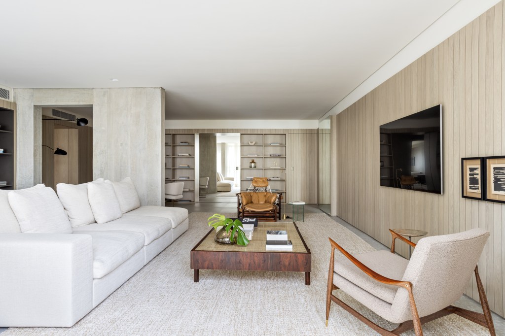 Marcenaria setoriza e decora apartamento de 156 m². Projeto de Alexandre Dal Fabbro. Na foto, sala de estar com TV, sofá, mesa e poltrona.