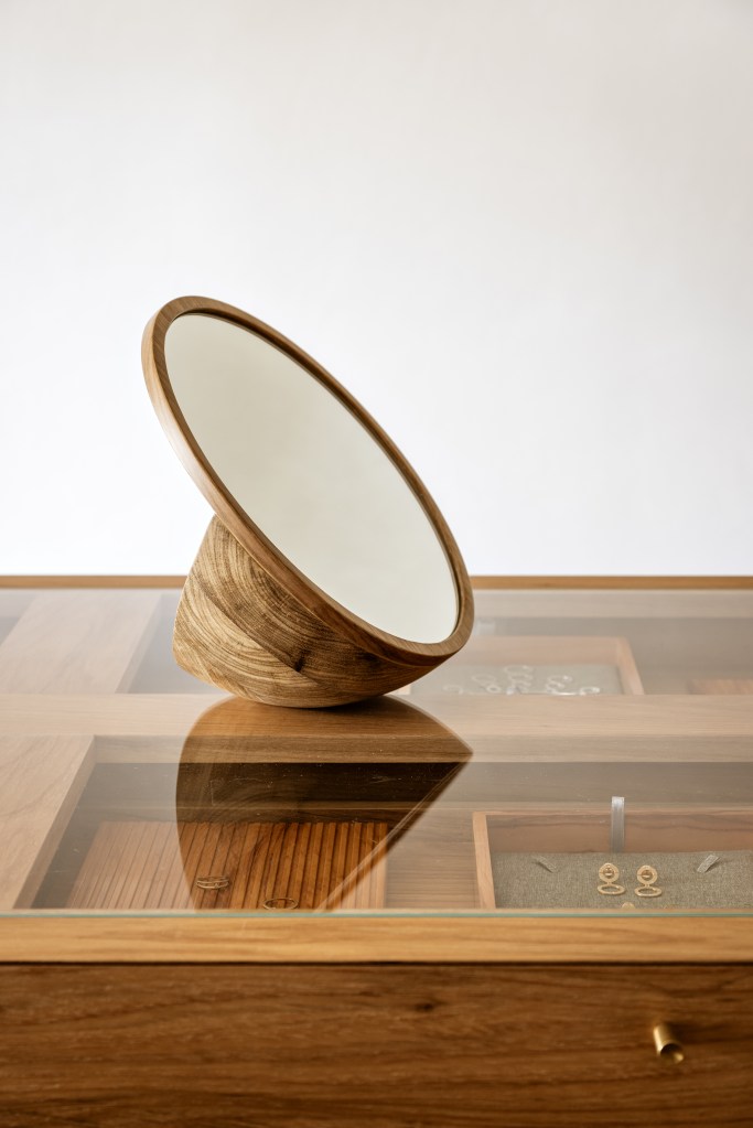 Mármore e madeira marcam showroom minimalista de joalheira. Projeto de Marina Salles Arquitetura. Na foto, vitrine de joias, espelho.
