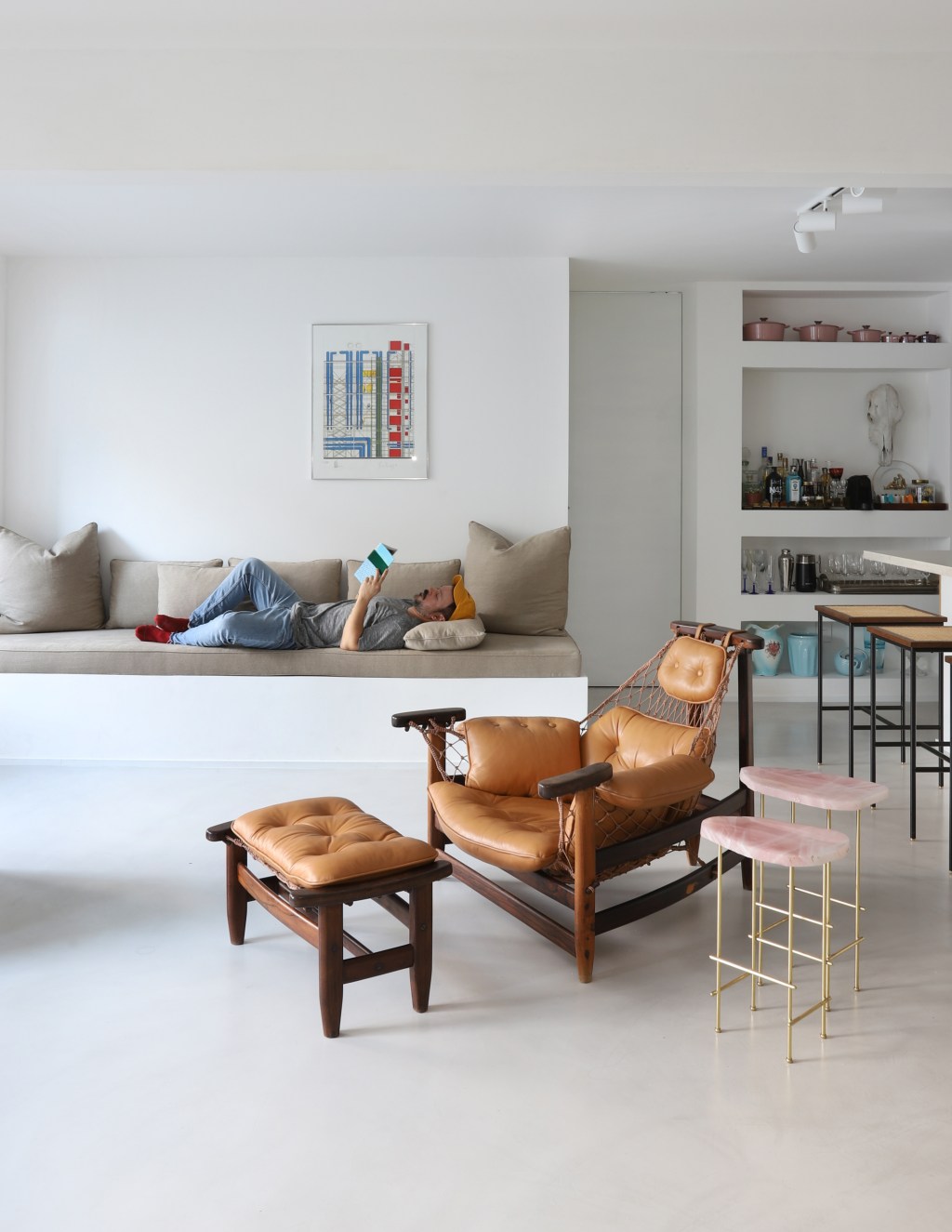 Móveis feitos de alvenaria expõem peças de design em apê de 150 m². Projeto de Rodra Cunha. Na foto, sala com sofá de alvenaria e poltrona.