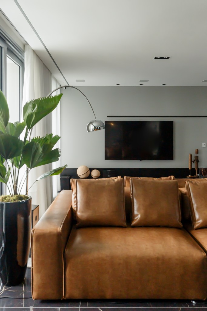Móveis soltos e paleta sóbria deixam apê de 190 m² atemporal e elegante. Projeto de NK Arquitetura. Na foto, sala de estar integrada, sofá de couro bege.
