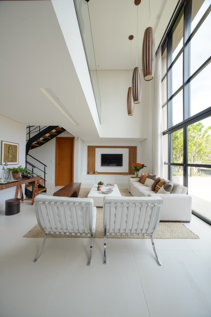 No mesmo prédio, arquiteta cria seu escritório e sua cobertura residencial. Leticia Nanneti Arquitetura e Interiores. Na foto, sala de estar, pé-direito duplo, sofá branco, mesa de centro branca.