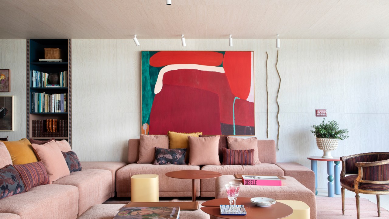 Painéis de madeira e tons de rosa criam decoração em homenagem ao feminino. Projeto de Marcelo Salum para a CASACOR São Paulo 2024. Na foto, sofá rosa, quadro, pufes amarelos.
