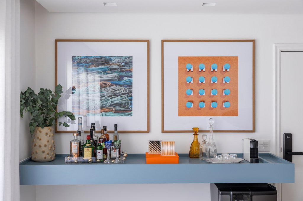 Papel de parede de formiga traz irreverência a este apê de 153 m². Projeto Next Arquitetos. Na foto, bar com aparador azul, vaso e quadros.