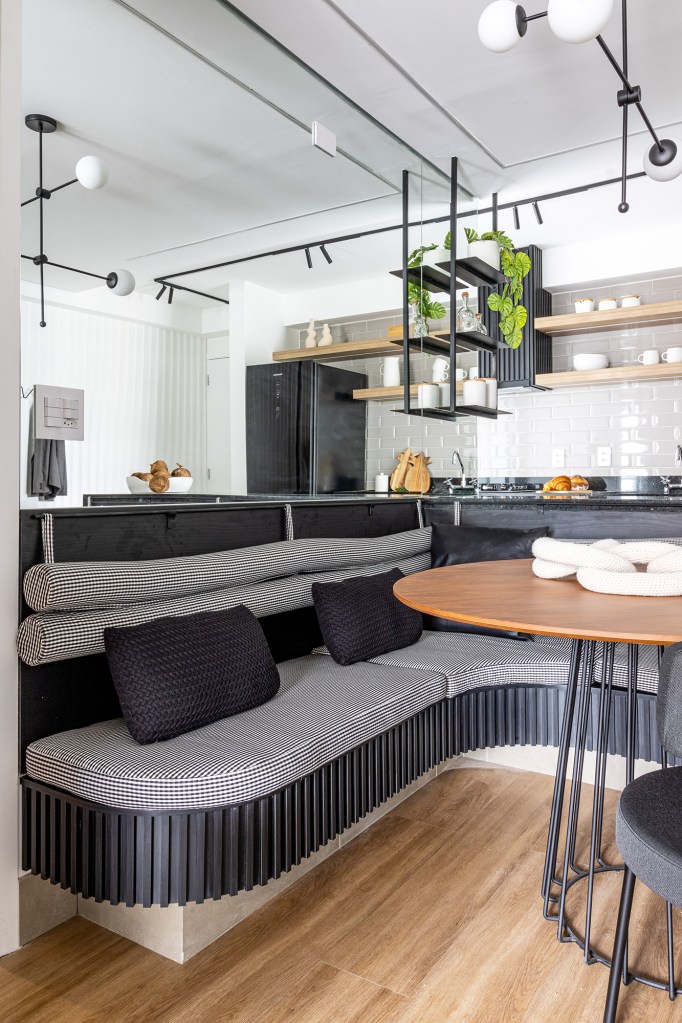 Prateleiras suspensas e muxarabi otimizam o espaço neste apê de 75 m². Projeto de Agê Arquitetura. Na foto, cozinha com canto alemão, mesa redonda e banco-bau.