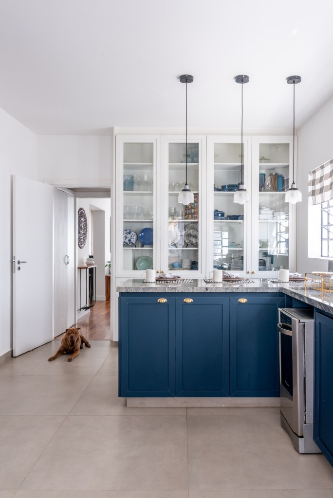 Reforma em casa alugada cria cozinha externa e sala com boiseries. Projeto de Abrazo Interiores. Na foto, armários azuis, portas de vidro, cozinha campestre.