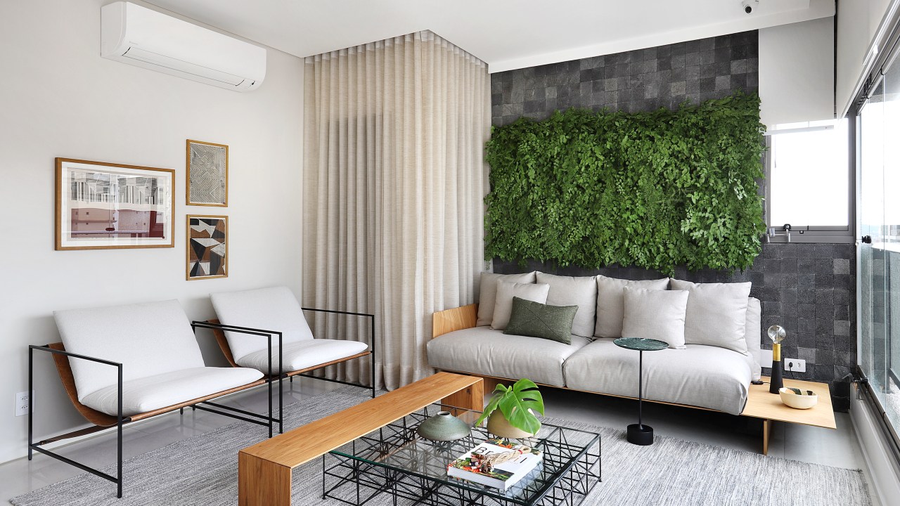 Reforma em apê cria três suítes lindas e área gourmet na varanda. Projeto de Carolina Gava. Na foto, sala de estar, sofá cinza, jardim vertical.