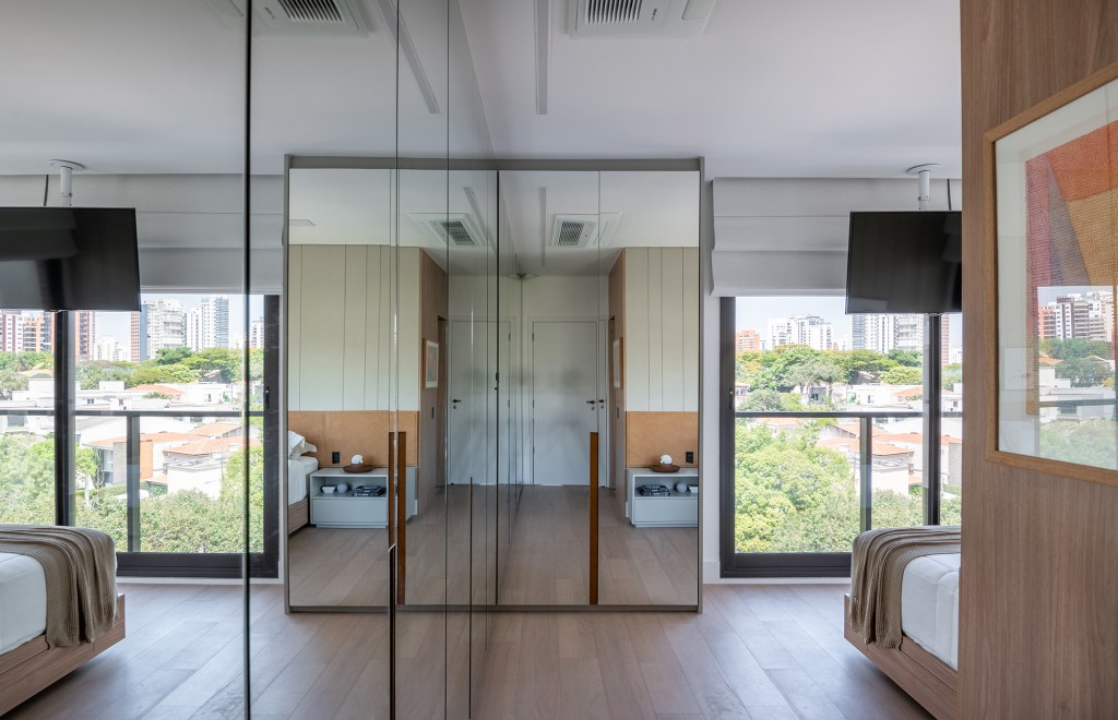 Vista 180º para o Ibirapuera e banheiro SPA marcam este apartamento. Projeto de Ana Carolina Queiroz. Na foto, quarto com armario espelhado e tv suspensa.