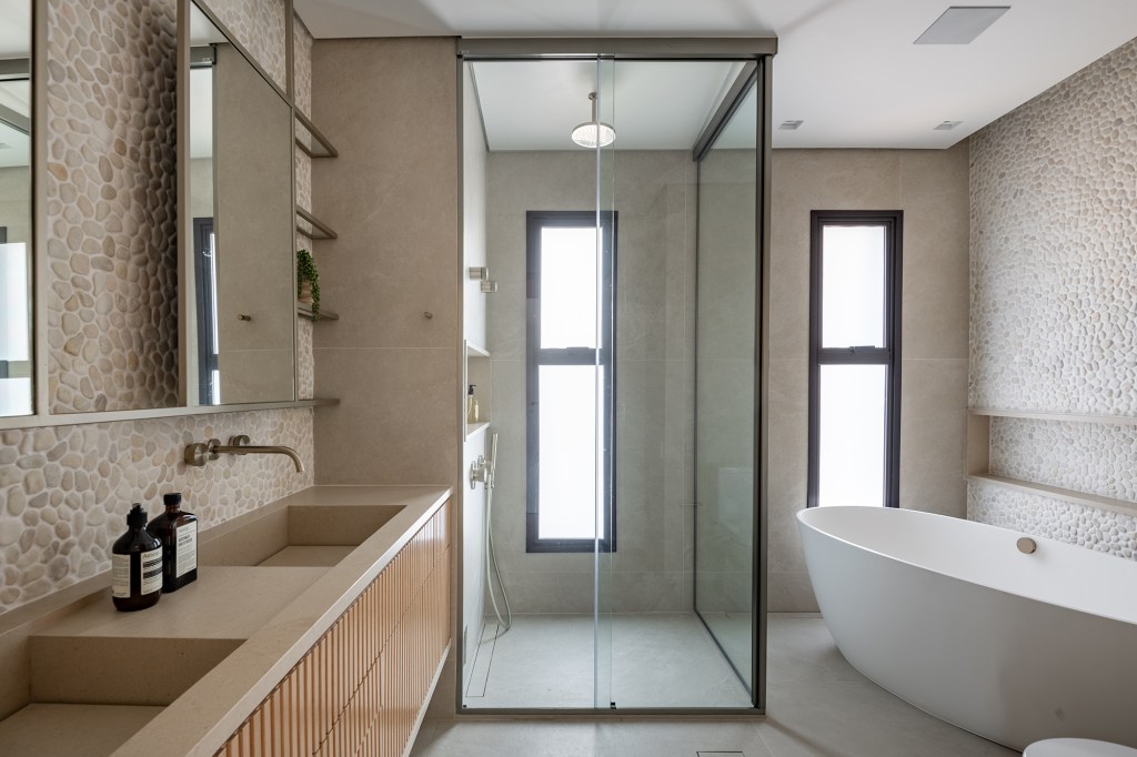 Vista 180º para o Ibirapuera e banheiro SPA marcam este apartamento. Projeto de Ana Carolina Queiroz. Na foto, banheiro spa com seixos na parede e banheira.