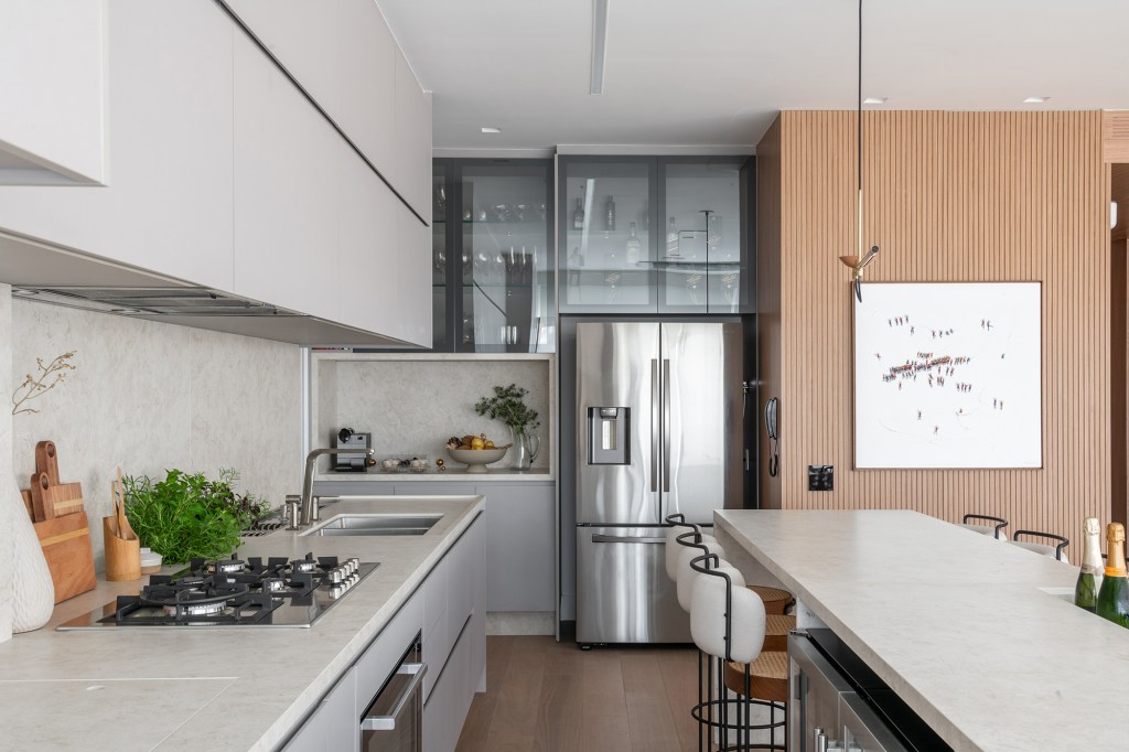 Vista 180º para o Ibirapuera e banheiro SPA marcam este apartamento. Projeto de Ana Carolina Queiroz. Na foto, cozinha com bancada de pedra, bar e churrasqueira.
