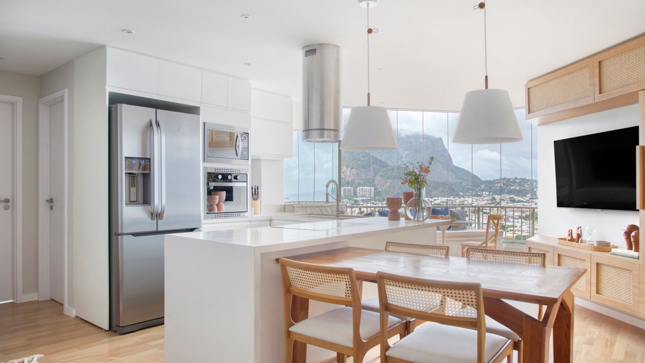 Apartamento de 90 m² apresenta design com toques praianos. Projeto do escritório Memoá Arquitetos. Na foto, cozinha e sala com vista do Rio de Janeiro