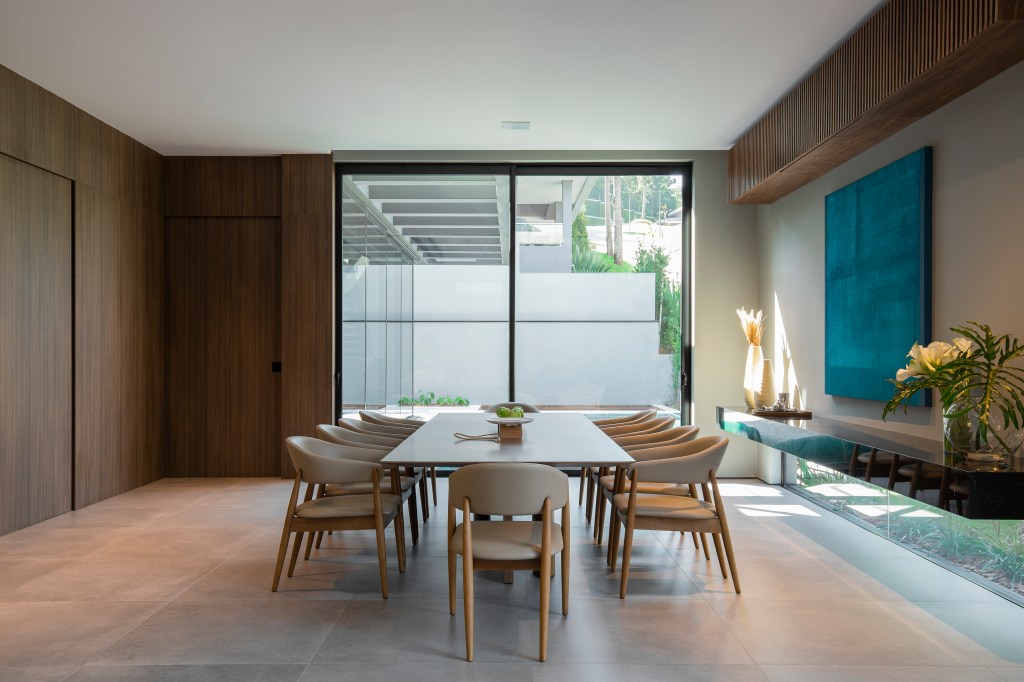 Apê de 500 m² é trabalhado em tons sóbrios e muita madeira. Projeto do escritório Gabriela Casagrande Arquitetura. Na foto, sala de jantar com mesa extensa