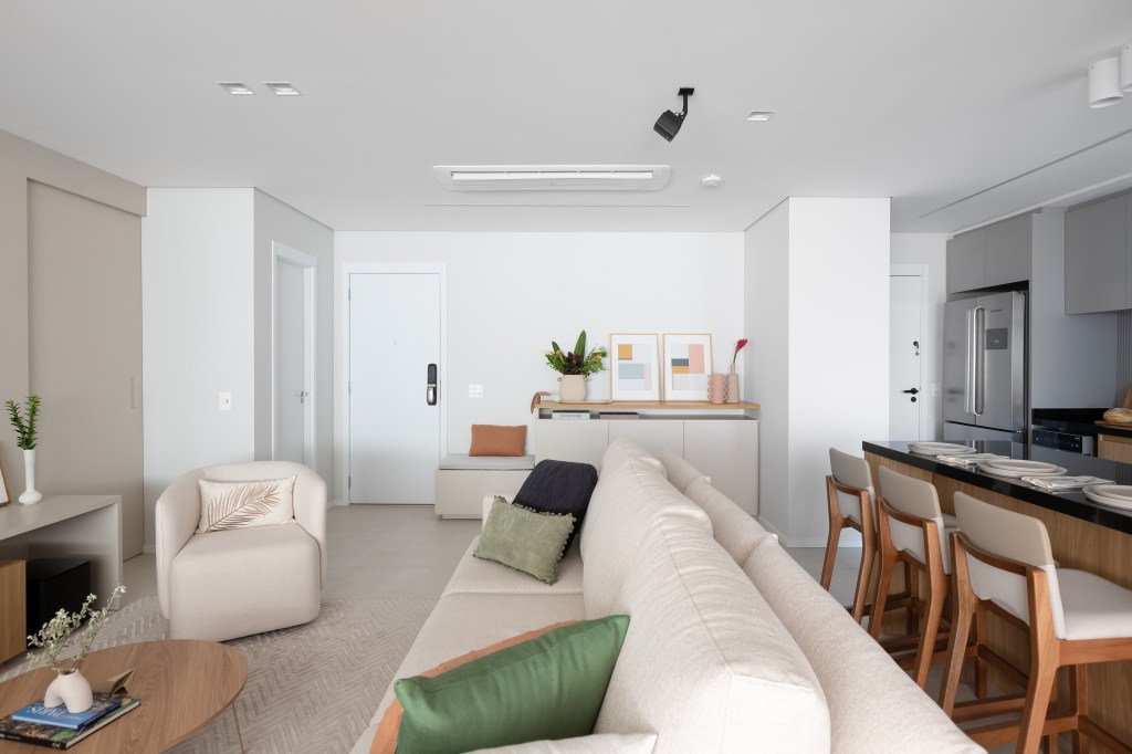 Aconchego e praticidade: apartamento de 126m² possui porcelanato acinzentado neutro e vinílico. Projeto do Estúdio Bena. Na foto, sala de estar e cozinha integradas