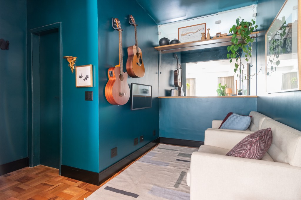 Apartamento térreo ganha brinquedoteca com papel de parede tropical. Projeto de Abrazo Interiores. Na foto, parede azul, piso de madeira, violões na parede.
