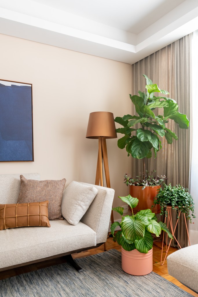 Apartamento térreo ganha brinquedoteca com papel de parede tropical. Projeto de Abrazo Interiores. Na foto, sala de estar, sofá bege, plantas, luminária de piso.