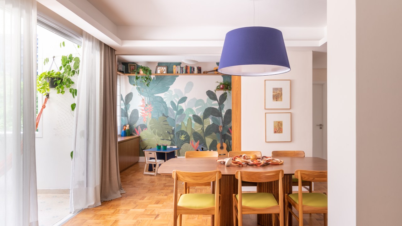 Apartamento térreo ganha brinquedoteca com papel de parede tropical. Projeto de Abrazo Interiores. Na foto, sala de jantar, luminária azul, mesa de madeira.
