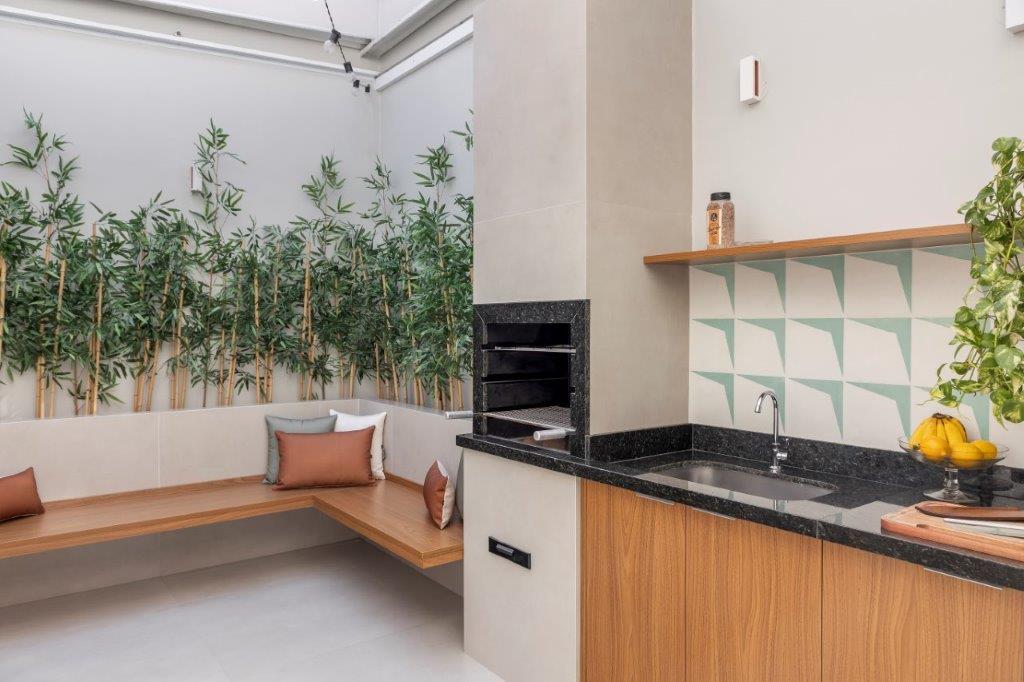 Casa de 146 m² ganha cozinha verde clara e área externa com churrasqueira. Projeto de Camila Bischoff. Na foto, área externa, jardim, parede de azulejos, bancada preta.